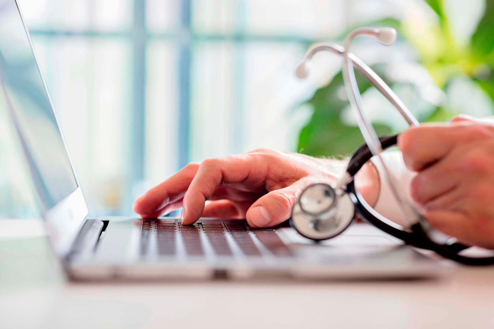 Healthcare professional hands touching a laptop keyboard