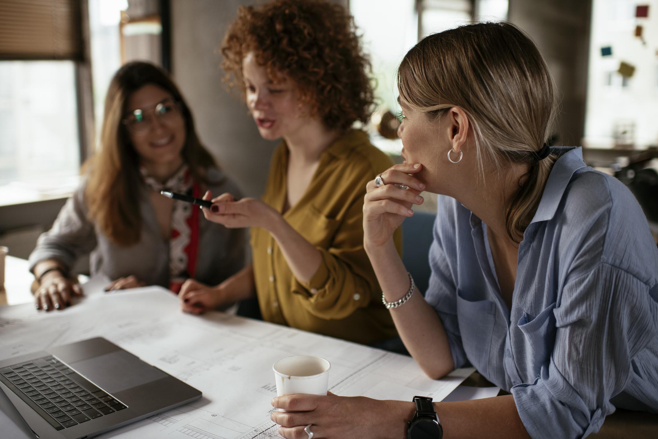 Women sitting around a laptop having a conversation