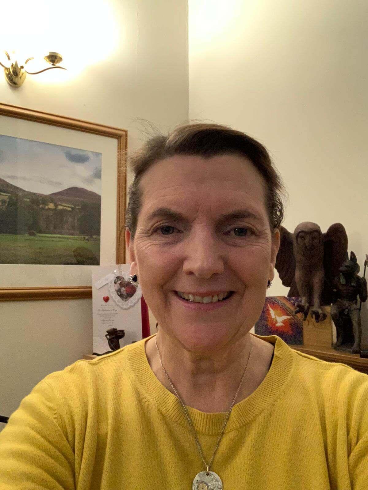 A woman in a yellow jumper smiling