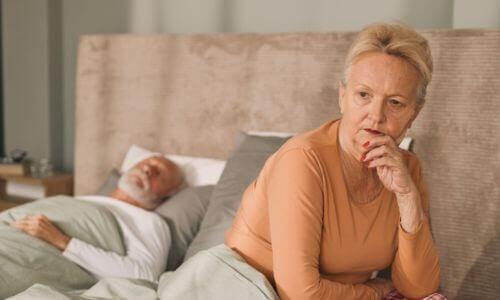 Woman sat on bed looking pensive