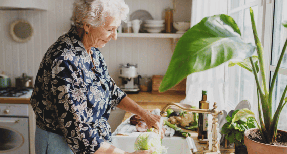 Older woman preparing a lettuce in the sink
