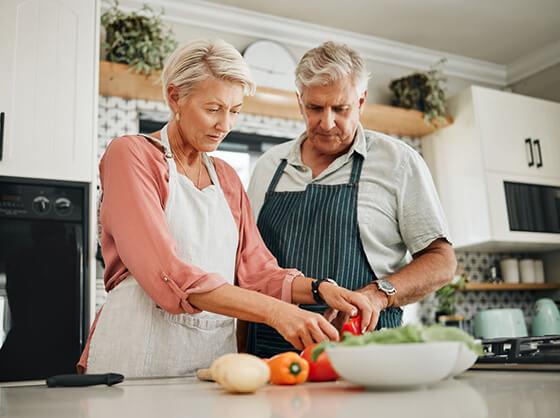 A couple cooking in the kitchen with peppers