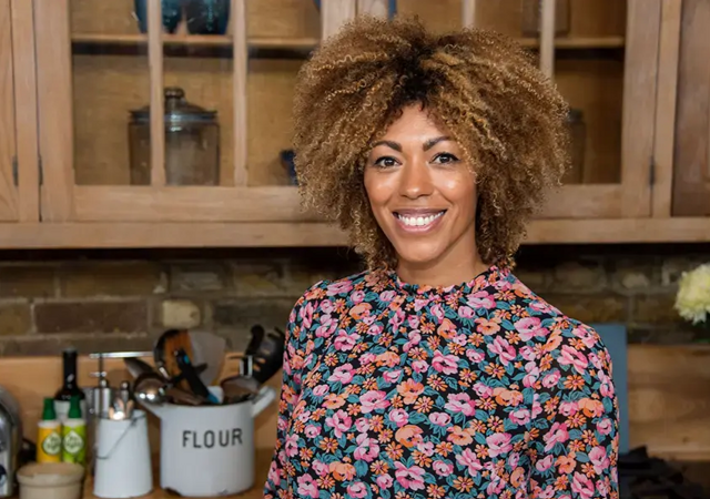 Dr Zoe Williams smiling to camera in her kitchen