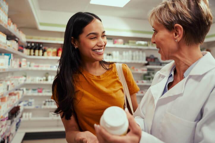 A woman talking to a pharmacist in a shop