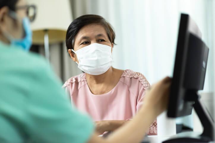 A doctor showing a woman test results on screen