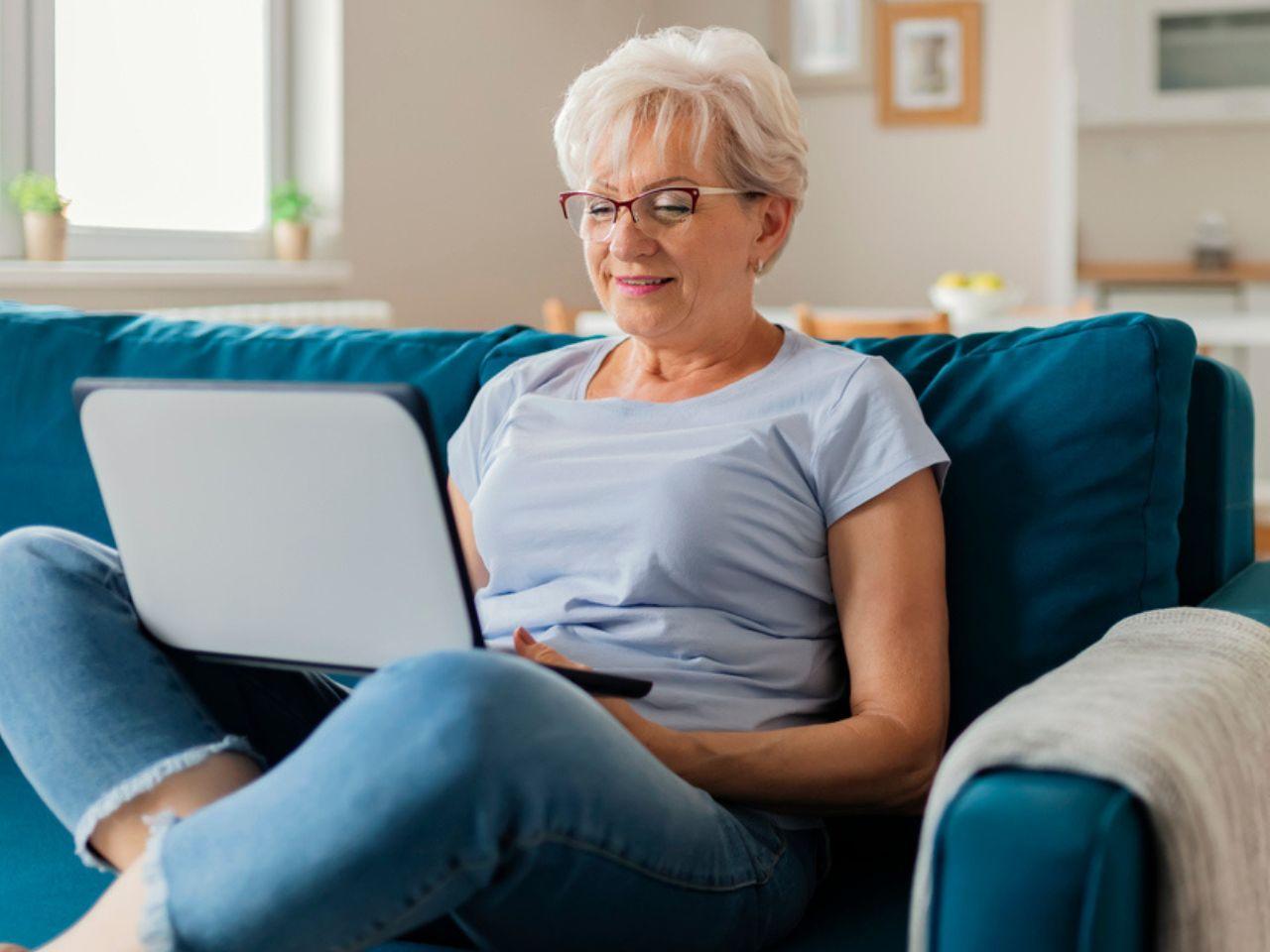 A woman sat on a sofa using a laptop