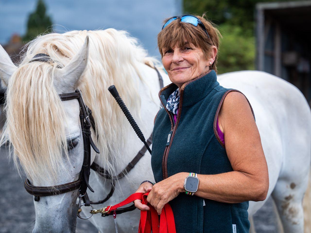 A woman holding the reins of a horse
