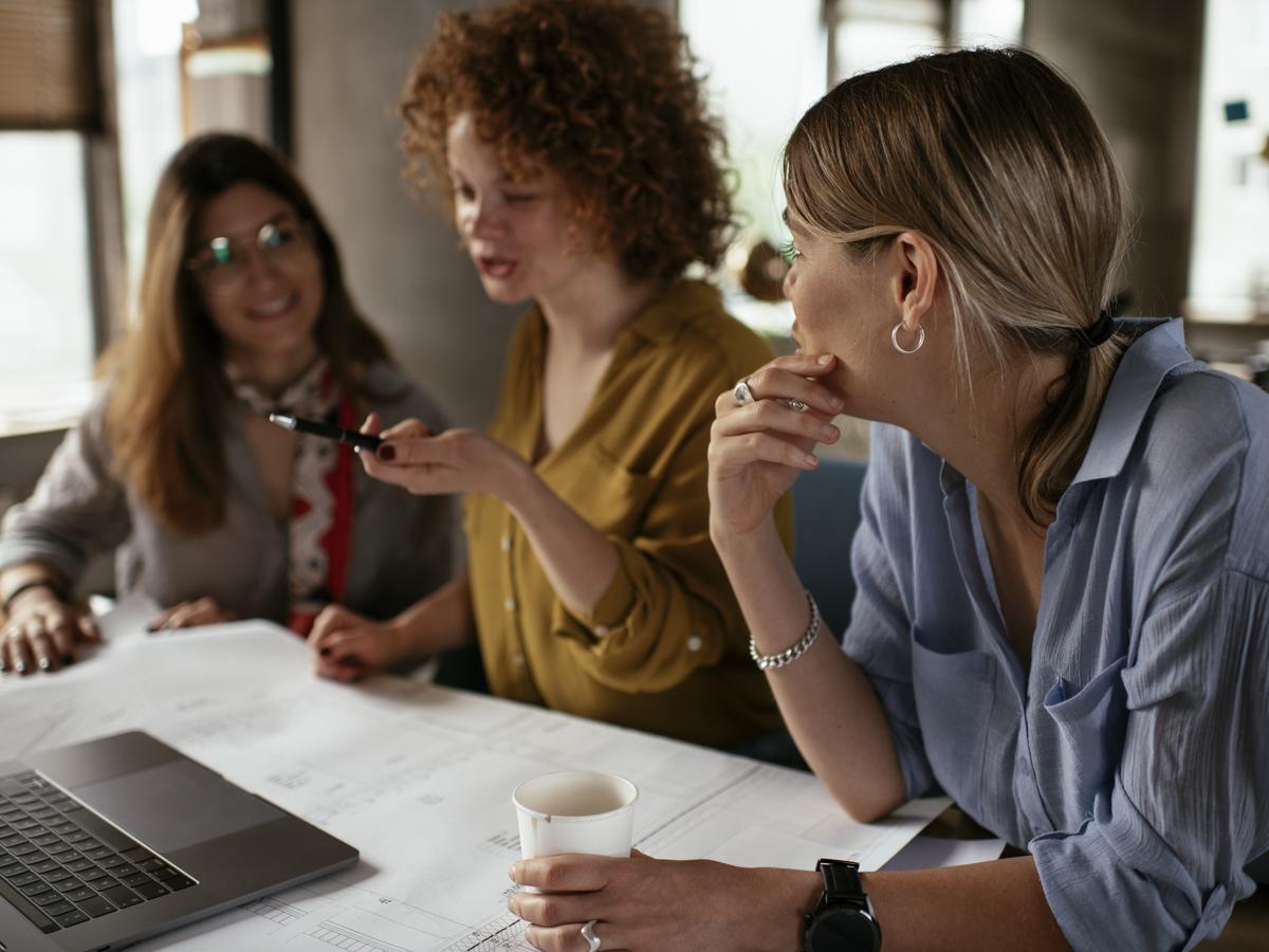 Women sitting around a laptop having a conversation