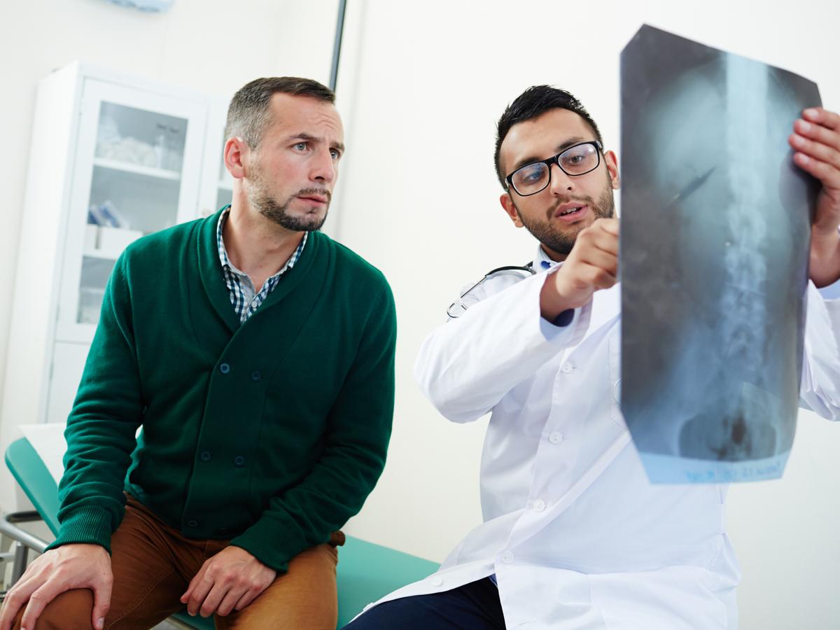 Doctor shows spinal xray to young man who looks concerned