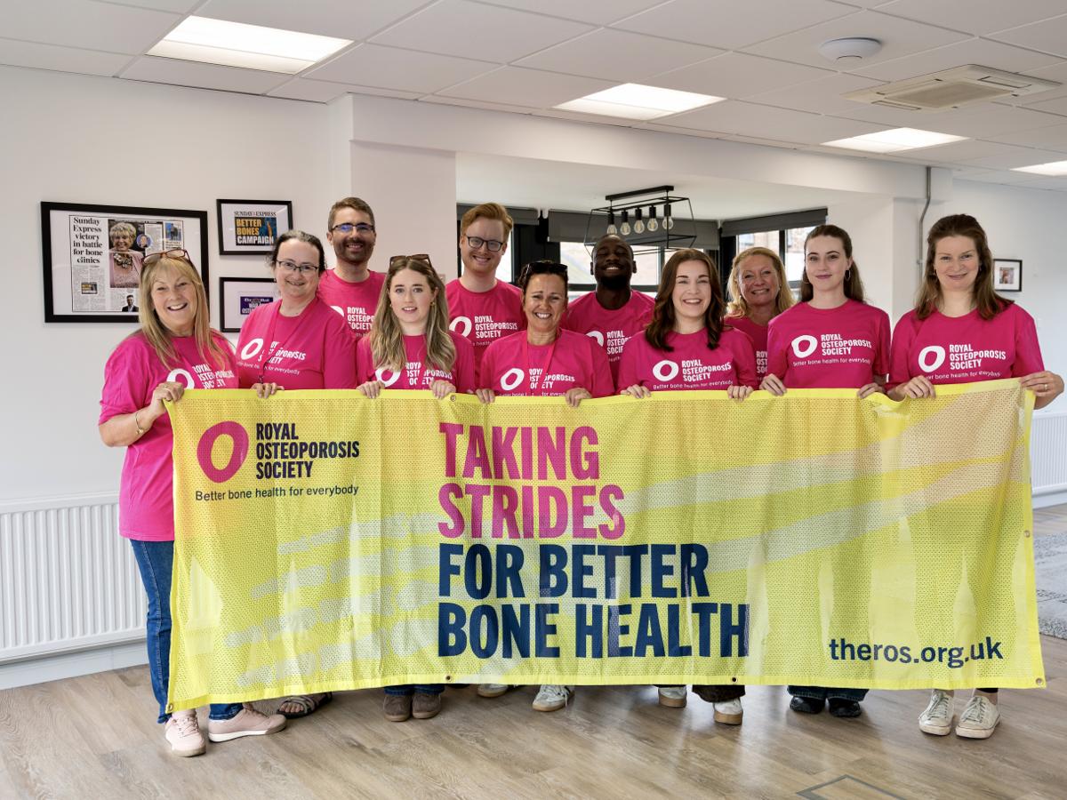 A group of ROS staff standing with a charity banner