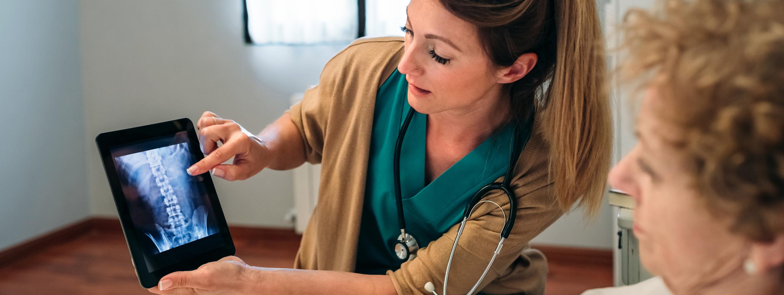 A healthcare professional showing a patient a scan of a spine